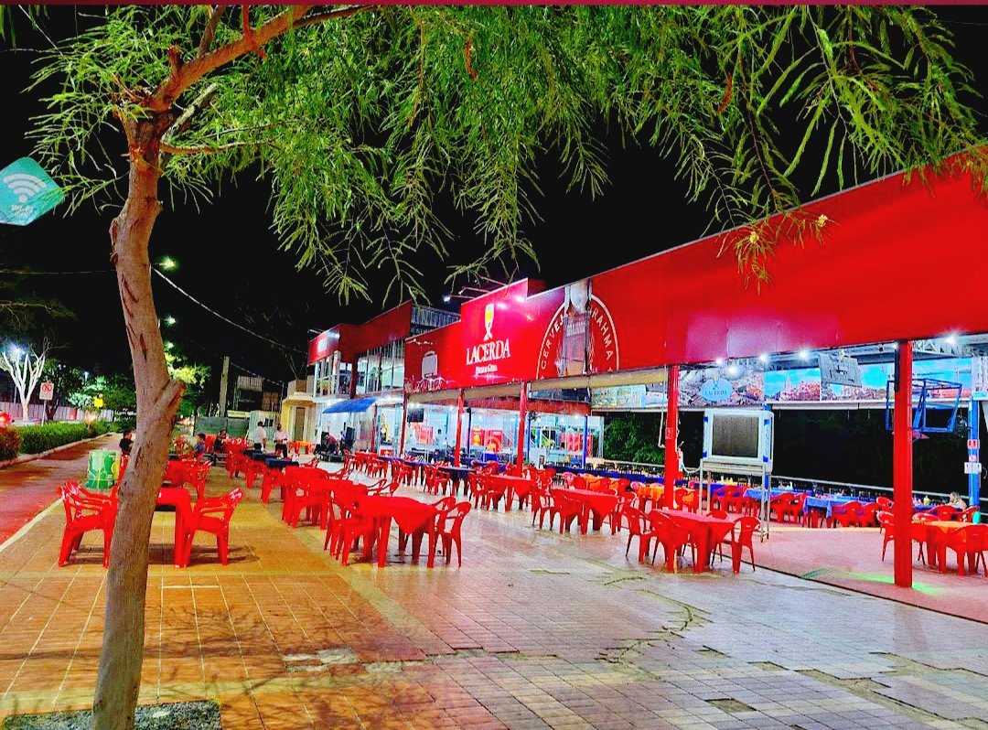 Fachada vermelha do Lacerda na orla à noite, com mesas na calçada