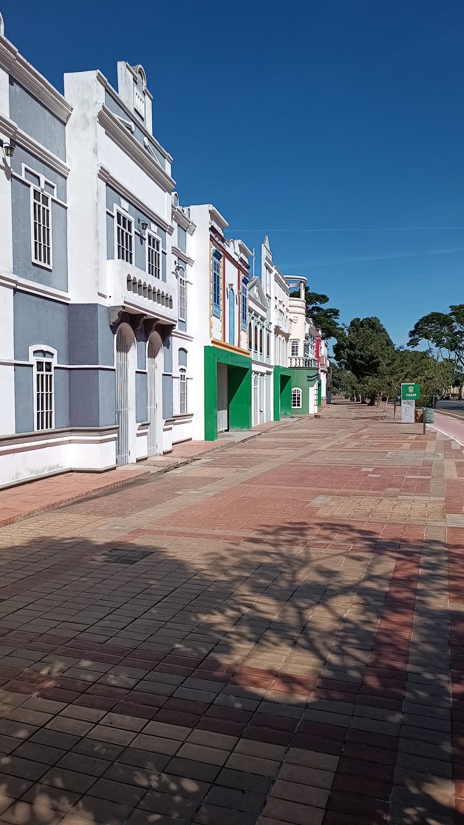 Rua histórica e colorida da orla do Porto, em Cuiabá, com calçada de tijolos e céu azul