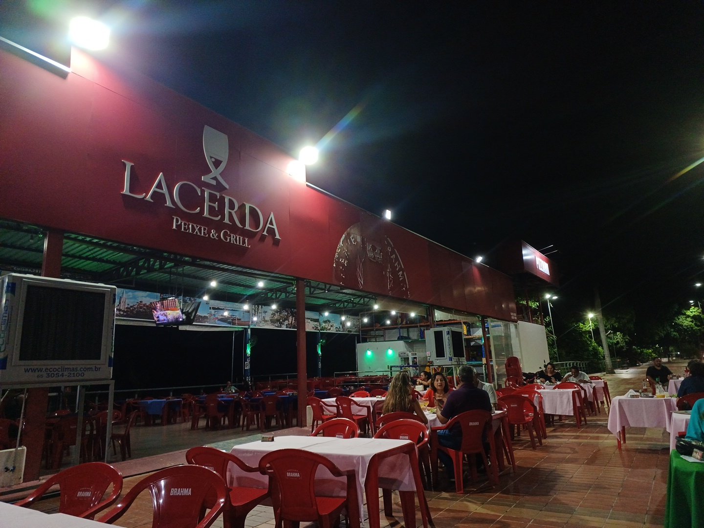 Fachada iluminada do Lacerda Peixe e Grill à noite, com o letreiro aceso
